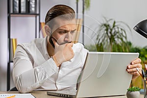 Irritated tired businessman working on laptop website problem, computer virus data loss by hacking