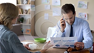 Irritated wife trying to talk with busy husband in business suit, wrangle photo