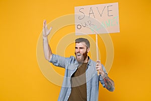 Irritated young protesting man hold protest sign broadsheet placard on stick rising hand scream isolated on yellow