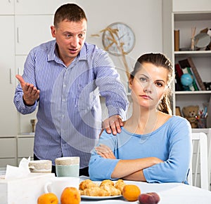 Irritated young spouses quarrelling in home kitchen interior photo