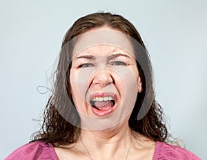 Irritation and disgust on the face of an adult woman, portrait on grey background, emotions series