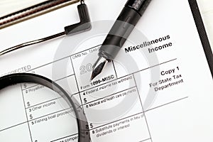 IRS Form 1099-misc Miscellaneous income blank on A4 tablet lies on office table with pen and magnifying glass photo