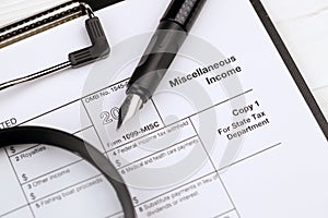 IRS Form 1099-misc Miscellaneous income blank on A4 tablet lies on office table with pen and magnifying glass photo