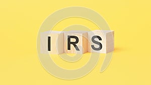 IRS - text on wooden cubes, on yellow background. Internal Revenue Service concept photo