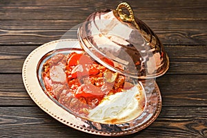 Iskander Kebab is a Turkish dish with meat, spices and vegetables on a traditional copper platter bakir Sahan Kayik . Wooden dark