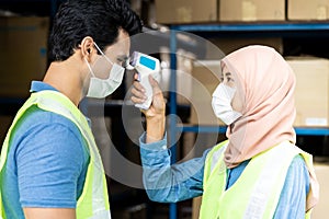 Islam Muslim asian warehouse worker taking temperature to worker
