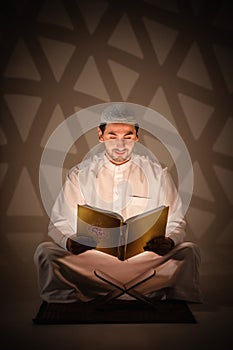 Muslim man holding holy quran book reading and study quran book in dark room photo