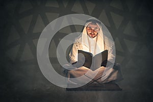 Arabic muslim man holding holy al quran book reading and study al quran book photo