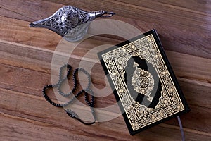 Islamic book Quran on the wodden board with a rosary and aladdin lamp -Ramadan /Eid Concept.