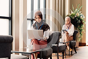 Islamic ethnic businesswomen working in stylish cafe