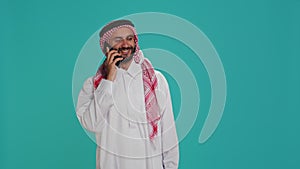 Islamic guy in robe texting on phone