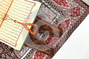 Islamic Holy Book Quran on wood carving rahle with rosary beads and prayer rug on  white background. Kuran the holy book o photo