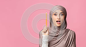 Islamic woman having idea, raising pencil with excited face expression