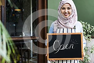 Islamic woman small business owner holding blackboard with smiling