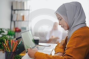 Islamic woman wearing hijab headscarf studying online with laptop