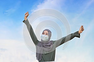 Islamic woman, wearing a mask, cheerfully raised both hands