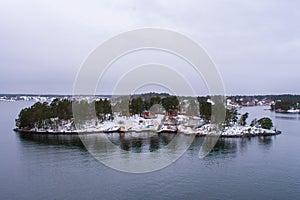 An island covered with little snow, trees and wooden houses