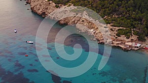 Island Ibiza beach sailing boats in the bay. Smooth aerial top view flight drone