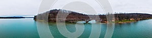 an island in a lake with a bridge over it near a forested area