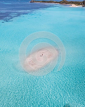 an island in the middle of clear blue water with white sand