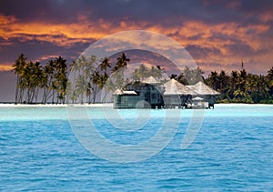 Island in ocean, overwater villas at the time sunset