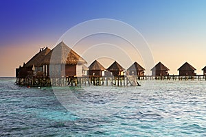 Island in ocean, overwater villas at the time sunset