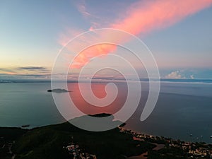 Island in the ocean with pink clouds