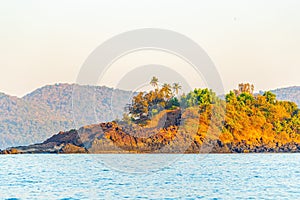 an island with orange grass and palm trees by water on shore