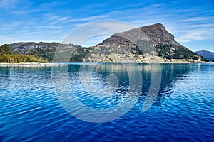 Island with rocks and trees in the fjord in front of the open sea in Norway