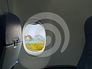 Island, sea and mountain view from window of airplane. Travel, vacation and journey concept