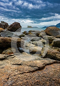 Island seen through rocks at Juliao Beach in Ilhabela, Sao Paulo - Brazil,