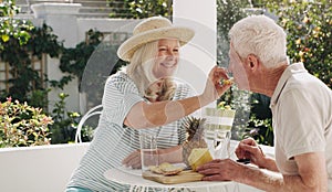 Isnt this delicious. a happy senior couple sitting outside together and enjoying a snack.