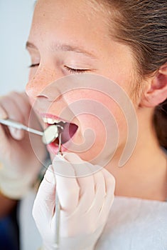 This isnt going to hurt a bit. Closeup shot of a young girl having a checkup at the dentist.