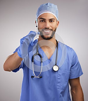 This isnt going to hurt. a handsome young nurse standing alone in the studio and holding a syringe.