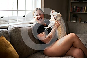 Isnt he just adorable. Cropped portrait of an attractive young woman smiling while holding her dog in her living room at