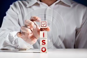 ISO standards, quality control certification approval. Businessman puts a cube on top of wooden cubes with the word iso