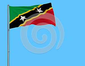 Isolate flag of Saint Kitts and Nevis on a flagpole fluttering in the wind on a blue background