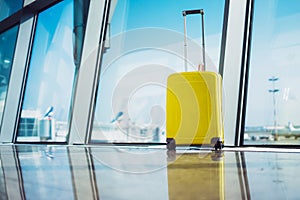 Isolate traveler tourist yellow suitcase at floor airport on background large window, bright luggage waiting in departure lounge
