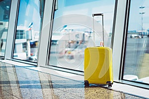 Isolate traveler tourist yellow suitcase at floor airport on background large window, bright luggage waiting in departure lounge