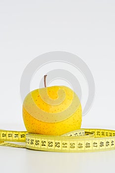 Isolated apple and measuring tape suggesting diet concept