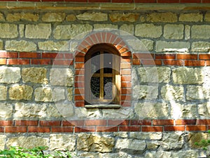 An isolated arched church monastery chapel window and massive stone wall background.