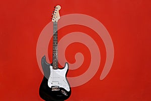 Isolated black and white electric guitar on red background