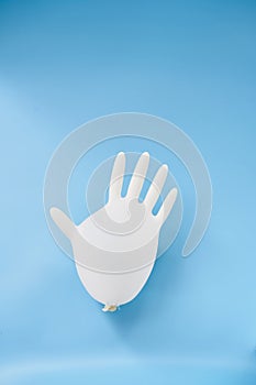 An isolated blown-up latex glove on a blue background. Covid-19 personal protection. Latex glove balloon.