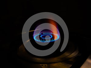 Isolated blue flame with orange shade of gas burner at black background