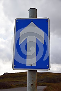 Isolated blue and white one way sign UK with white arrow on blue background