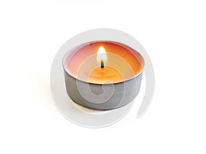 Isolated burning round candle. Front view of round tea light on white background. Burning flame in small round candle