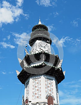 Chinese pagoda clock tower soars in blue sky