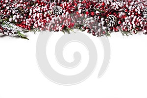 Isolated Christmas holiday decoration with snowy red berries and pine cones on white background, plant Christmas border