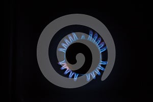 Isolated close up shot of a blue and orange circular fire with small flames on the perimeter coming from a kitchen gas stove and