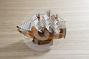 Isolated close-up of a souvenir wooden ship on a light wooden background